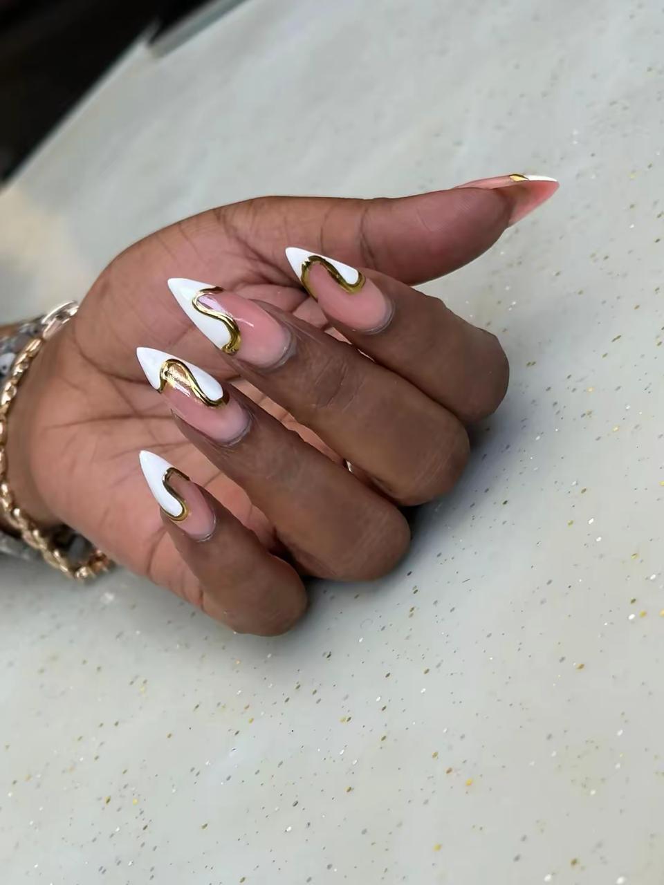 White stiletto nails with gold swirl art